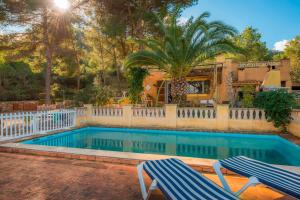 a swimming pool with two chairs in front of a house at Bonavista (Batle De Bonavista) in Felanitx