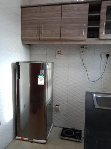 a stainless steel refrigerator in a kitchen with wooden cabinets at Stunning 2-Bed Apartment in Namugongo Town Kampala in Kasiyirize