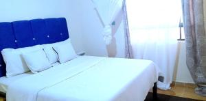 białe łóżko z niebieskim zagłówkiem w pokoju w obiekcie Maridadi place w mieście Kakamega