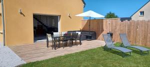 een patio met een tafel en stoelen en een parasol bij Le 25 A in Quettehou