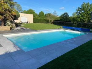 a swimming pool with blue water in a yard at Le Sancta Cécilia in Sainte-Cécile