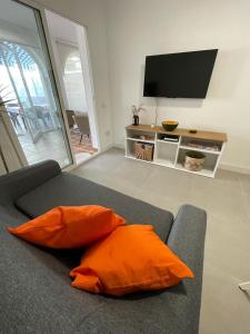 sala de estar con sofá y almohada naranja en Encantador Piso con Terraza y Piscina, en Benalmádena