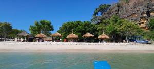 una playa con sombrillas, mesas y agua en Ekas beach guesthouse and restaurant, en Ekas