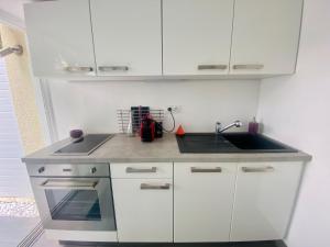 a kitchen with white cabinets and a sink at Villacampo in Le Grau-du-Roi