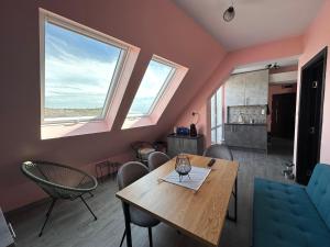 comedor con mesa, sillas y 2 ventanas en Sea Sky View Apartments en Balchik