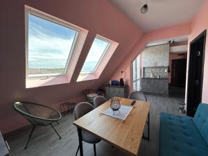 a dining room with a table and chairs and two windows at Sea Sky View Apartments in Balchik