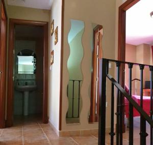 a hallway with a staircase with a mirror and a door at CASA RURAL EN URB LAs TRUCHAS-EL BOSQUE in El Bosque