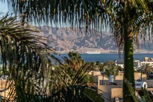 a view of the ocean and mountains from a palm tree at Eilat Beach House in Eilat