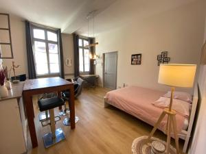 a bedroom with a bed and a desk and windows at Studio Papillon en plein cœur de ville in Saint-Omer