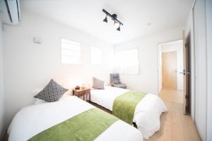 2 camas en una habitación con paredes blancas en Nagashima Riverside Condominium, en Hakuro