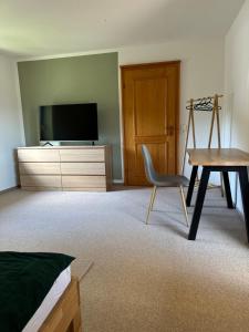Habitación con TV, silla y escritorio. en Bollenlodge - Ferienwohnung mit Ausblick und Top Lage, en Todtnau