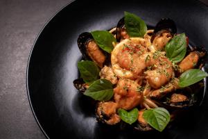 a black plate of food with shrimp and sausage at Hotel St.John Suites Adults Only in Tsilivi