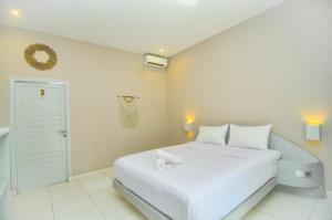 a white bedroom with a white bed and a door at Follow Your Dreams Gili Air in Gili Islands