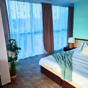 a bedroom with a bed and a large window at Апартамент FLAME in Sunny Beach