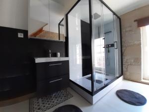 La salle de bains est pourvue d'une douche en verre et d'un lavabo. dans l'établissement Le relais des Colombes, à Creully