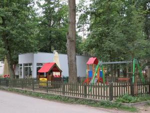 a playground behind a fence with a building at Nowa Holandia in Sieraków