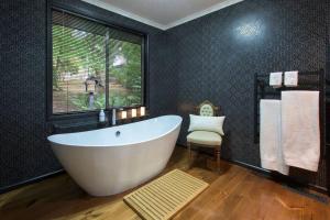 a bathroom with a large white tub and a window at The Beeches Olinda Accommodation in Olinda