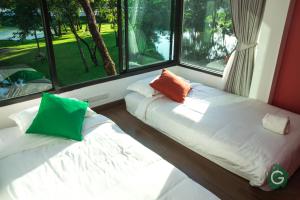two beds sitting in a room with windows at Green@Buriram in Buriram