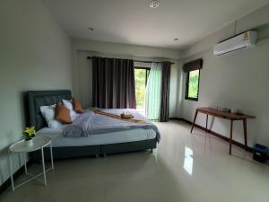 Schlafzimmer mit einem Bett, einem Tisch und einem Fenster in der Unterkunft สวัสดีปัวโฮมสเตย์ Sawaddee Pua Homestay in Pua