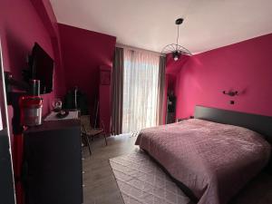 a bedroom with a pink wall with a bed and a desk at Sea Sky View Apartments in Balchik