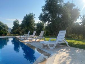 a row of white chairs sitting next to a swimming pool at Nefes URLA Villa Sea View. in Urla