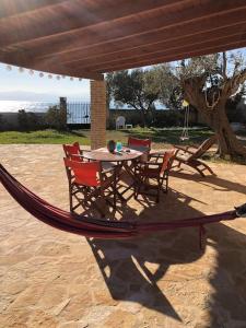a hammock with a table and chairs on a patio at House by the Sea at Skaloma, Loutraki in Vouliagmeni Lake