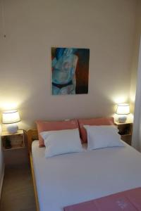 ein Schlafzimmer mit einem Bett mit zwei Lampen und einem Gemälde in der Unterkunft House by the Sea at Skaloma, Loutraki in Vouliagmeni-See