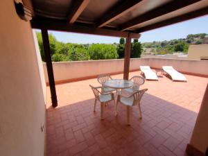 a patio with a glass table and chairs on a roof at La Pineta San Vito Apartment in San Vito lo Capo