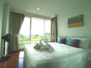 a bedroom with a white bed with a large window at Baan Sanploen Huahin Condo By KK in Hua Hin