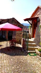 una mesa con una sombrilla roja en un patio en Casa do Charco Peneda Gerês, en Parada