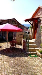a table with a red umbrella in a courtyard at Casa do Charco Peneda Gerês in Parada