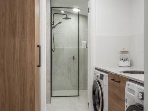 een badkamer met een douche en een wasmachine bij Central Bendigo Cottage Charm in Bendigo