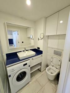 a bathroom with a sink and a washing machine and a toilet at Hotel Orbi city in Batumi