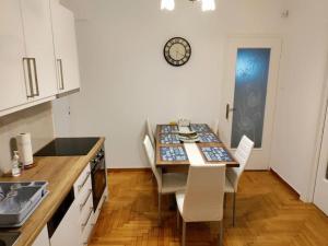 a kitchen with a table with chairs and a clock on the wall at VeryBeautifulSpaciousAppartment in Athens