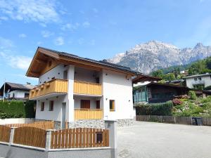 a white house with a wooden fence and mountains at Apartment SB77 Leogang in Leogang
