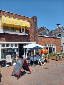 een tafel met een parasol en stoelen voor een gebouw bij BnB-Heirhuys in Visvliet