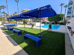 a patio with blue benches and an umbrella at Luxury beachfront apartment in Benalmadena Costa in Benalmádena