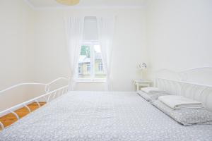 a white bedroom with a bed and a window at Ringi Apartments in Pärnu