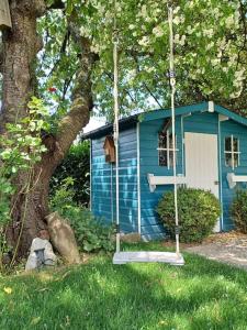 uma casa azul com um baloiço em frente a uma árvore em Ferienwohnung An den Linden em Kelmis