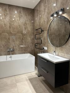 bagno con vasca, lavandino e specchio di Villa BEBRŲ NAMAI with Hot Tub a Ginduliai