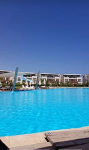 una gran piscina azul con edificios en el fondo en Amwaj Resort امواج الساحل الشمالى 2 نوم 2 حمام, en El Alamein