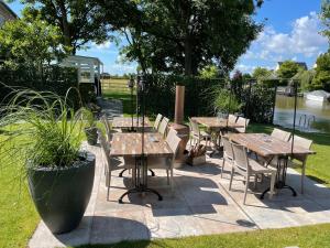 een patio met houten tafels en stoelen naast een rivier bij Harlingen Staete Wellness B&B Oase van rust en luxe in Harlingen