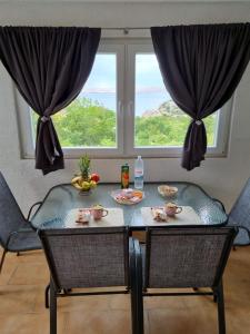 mesa y sillas con mesa y ventana en Apartmani 'Cvit', en Karlobag