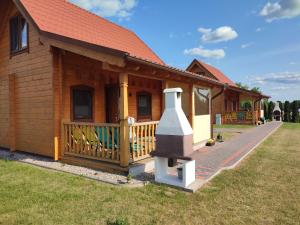 ein Holzhaus mit einer Veranda und einem Kamin in der Unterkunft Domki Blizniaki in Żywki