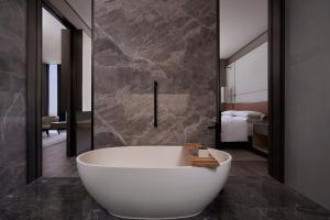 a bath tub in a bathroom with a bedroom at Tianjin Marriott Hotel National Convention and Exhibition Center in Tianjin