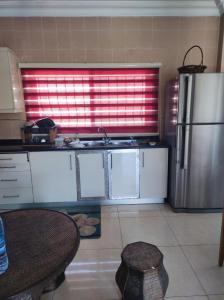 Il comprend une cuisine équipée d'un réfrigérateur en acier inoxydable et d'une table. dans l'établissement Noor Apartment, à Amman