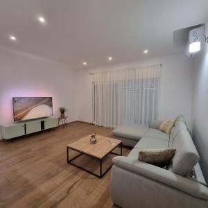 uma sala de estar com um sofá e uma televisão em Brand-new 3-bedroom apartments em Kaštela