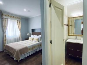 een slaapkamer met een bed, een wastafel en een spiegel bij Apartamento centro de O Grove in O Grove