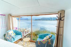 a room with two chairs and a view of the water at Titicaca tikary's lodge in Puno
