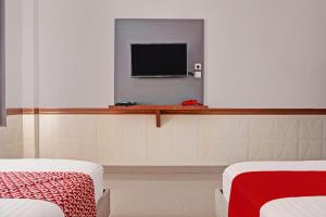Cette chambre comprend 2 lits et une télévision à écran plat. dans l'établissement OYO 92518 De Luna Hotel, à Banjarbaru